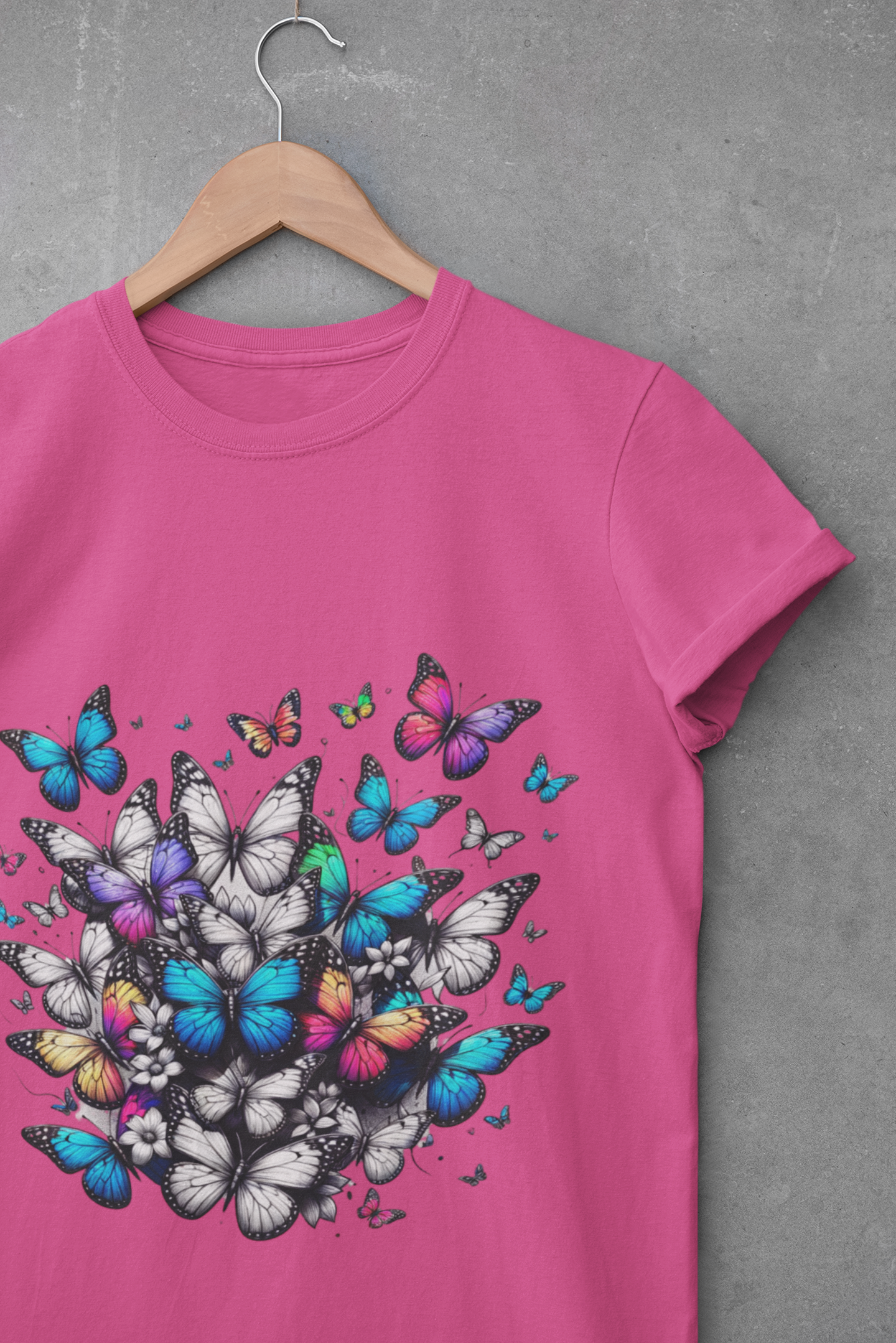 A pink unisex crew neck t-shirt with a colorful butterfly graphic design, displayed on a hanger against a grey background.
