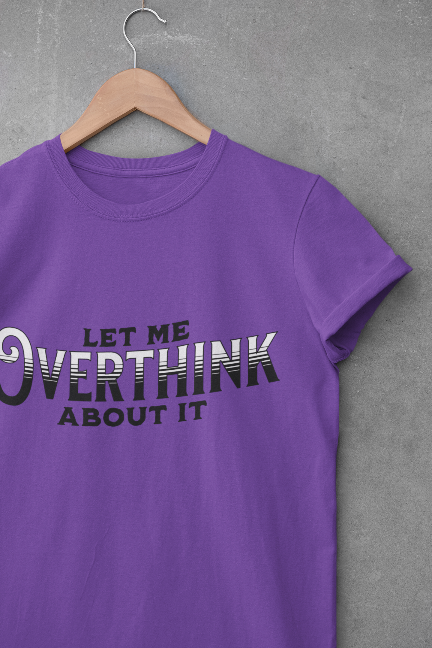 Purple graphic t-shirt on hanger with “Let Me Overthink About It” printed in bold lettering