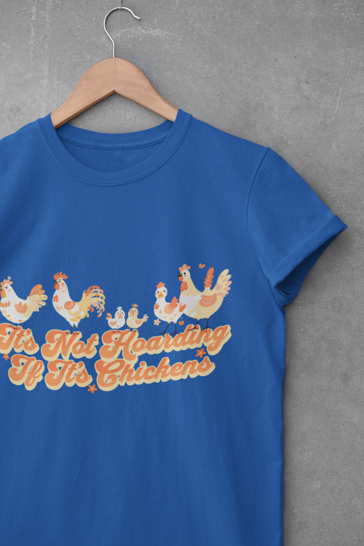 Royal blue unisex t-shirt with illustrated chickens and chicks above the phrase “It’s Not Hoarding If It’s Chickens” in playful retro text.