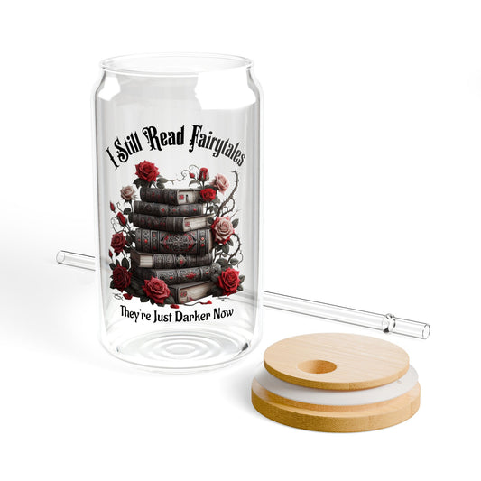 Glass tumbler with book and rose design, wooden lid, and straw on a white background