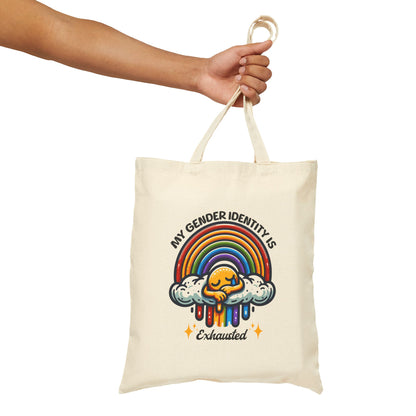 Tote bag with rainbow design and text held by a hand on a white background