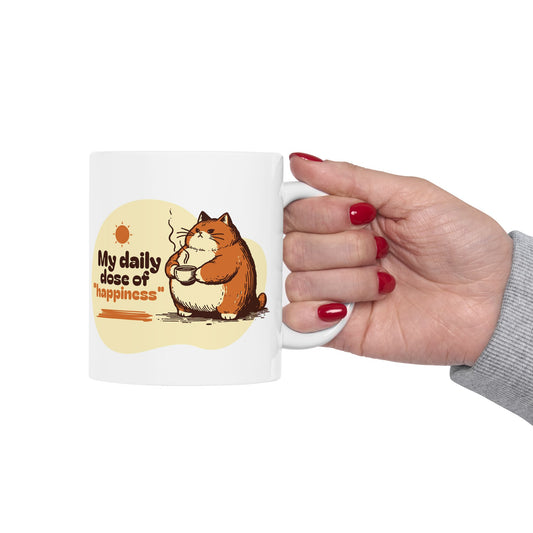 White ceramic mug featuring a chubby cat holding coffee with the text “My daily dose of happiness” in warm colors