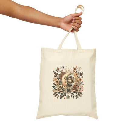Natural cotton tote bag with a celestial design featuring a sun and moon surrounded by earthy-toned flowers and leaves.