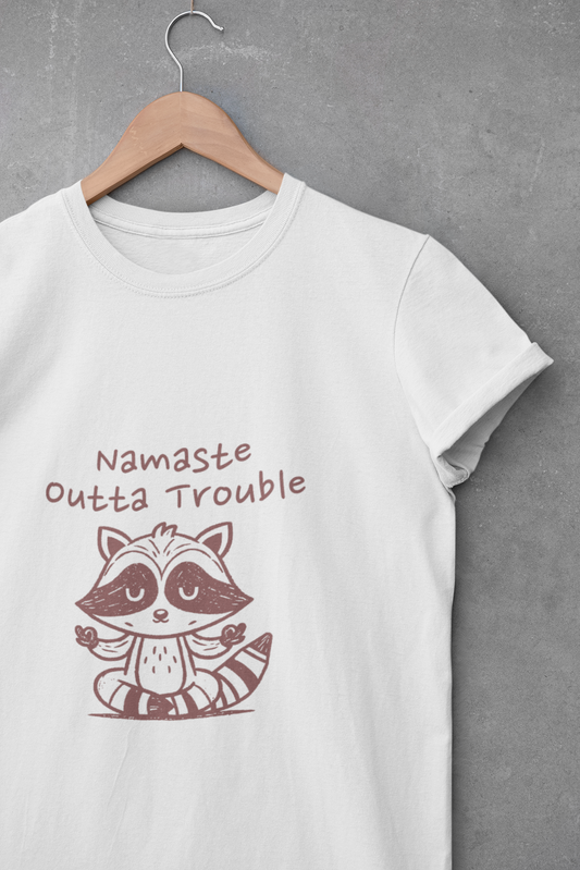 White t-shirt with a raccoon graphic and text 'Namaste Outta Trouble' on a gray background