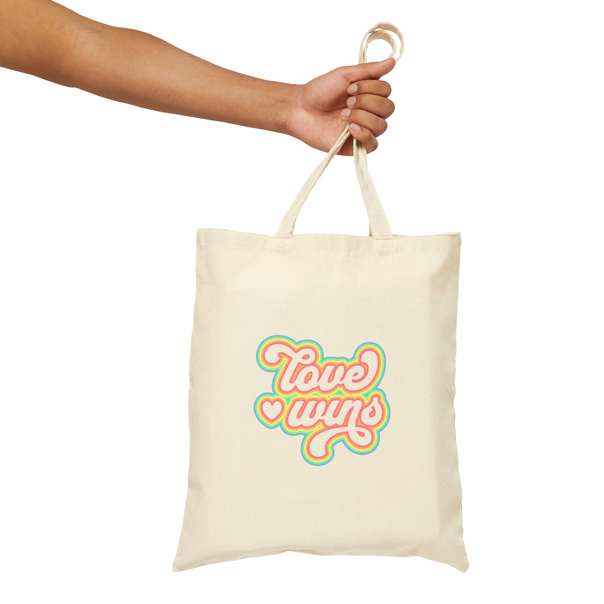 Tote bag with 'Love wins' text held by a hand on a white background