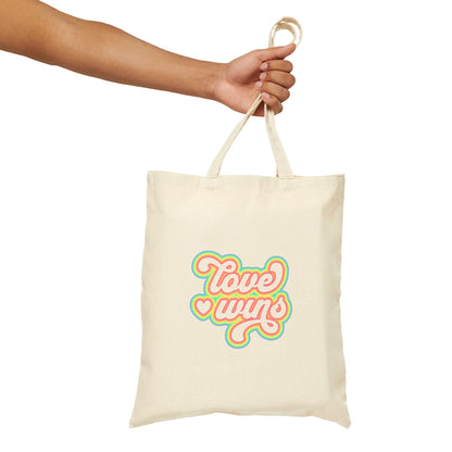 Tote bag with 'Love wins' text held by a hand on a white background